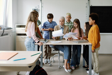 Multicultural tutor demonstrating pictures to students