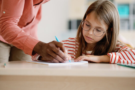 Tutor helping schoolgirl doing task 