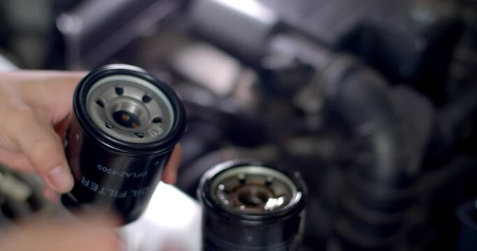 Apply fresh oil to the seal of a car oil filter during an oil change.Close up oil filter.Close up hands of mechanic doing car service and maintenance.