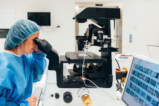 IVF Biologist in uniform working using microscope