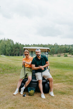 A man and a woman look at the camera sitting in a golf car