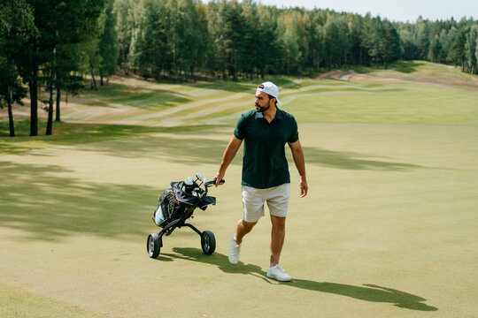 A man with golf equipment walks on a course