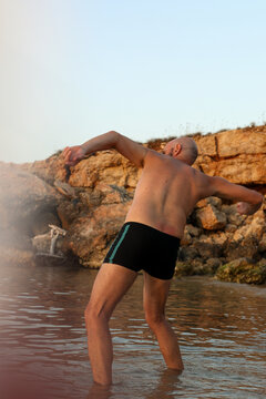 Man in black short playing in the sea doing ricochet with a stone