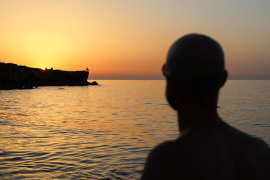 Sunset in the beach with gradient colours and out of focus man look it