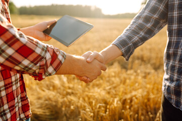 Handshake. Two farmer standing and shaking hands in a wheat field. Agricultural business. - obrazy, fototapety, plakaty