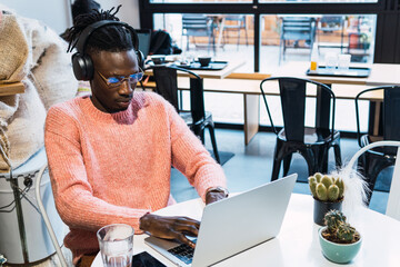 Black man in headphones working on laptop