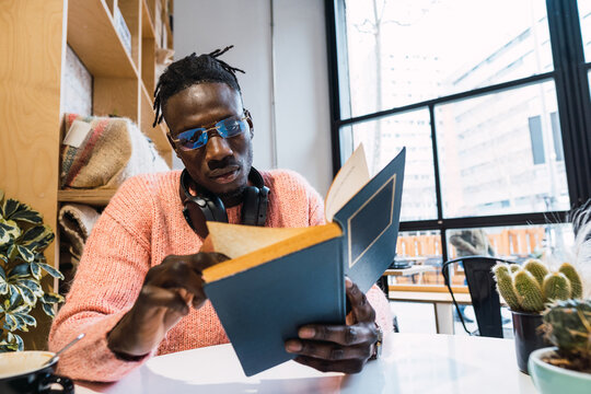 Black man reading book in cafe