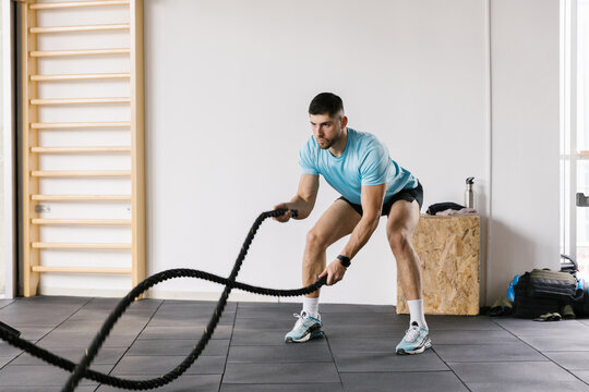 Lifestyle image of athlete male workout in the gym with a rope
