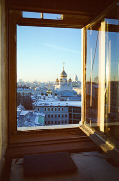 View through the window: Golden dome church and roofs covered in snow