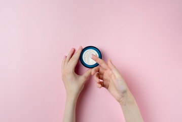 Female hand testing cream on pastel pink background