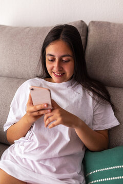 teen girl sitting on sofa at home with mobile phone