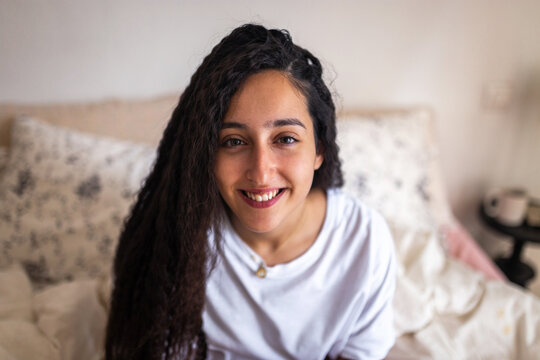 portrait of teen girl with curly hair in her bedroom
