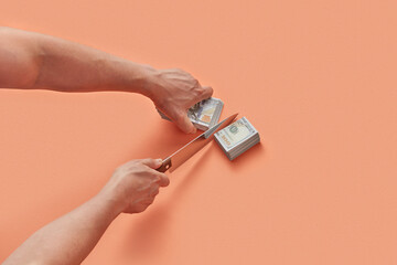 Close up of male hands cutting stack of dollar banknotes