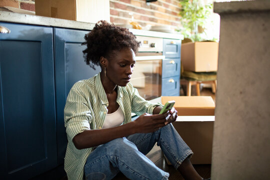 Woman using smartphone on floor with moving boxes around
