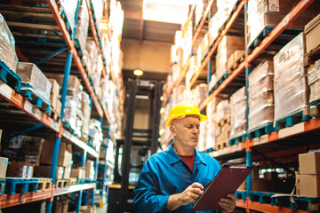 Mature warehouse manager with clipboard checking inventory