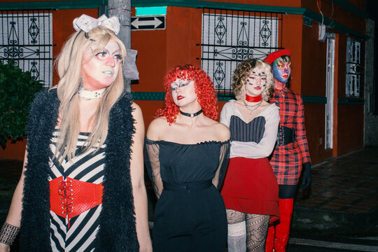 Four queer people walk in line through a zebra crossing