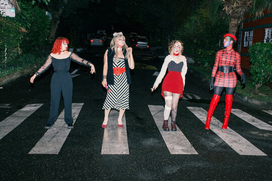 Four queer people stand on zebra crossing