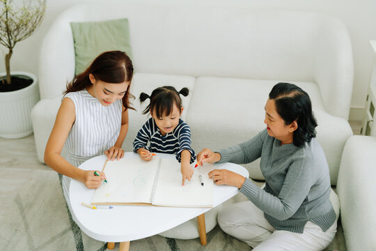 Children drawing, mother and grandmother watching