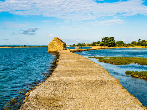 Amazing view of the tide mill and its dike at Arz Island in a bright sunny day, Morbihan gulf, Brittany, France

