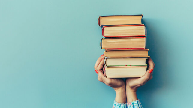 Woman hands holding pile of books over light blue background. book swap hobby relax time
