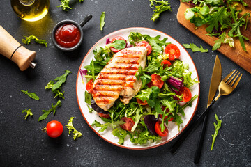 Green salad with chicken and fresh vegetables on black background. Keto diet, healthy food.