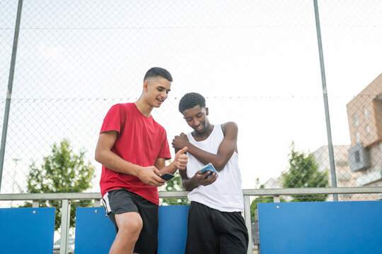 multiracial friends using mobile phone at basketball