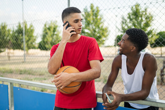 multiracial friends using mobile phone at basketball