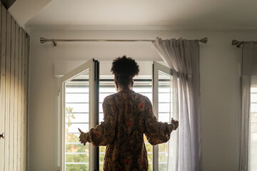 black woman at home looking out her bedroom window