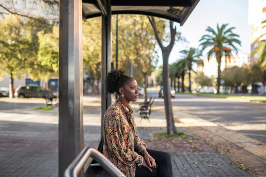black woman sitting at city bus stop