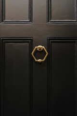 A closeup of a closed black door with a decorative door knocker exudes an air of sophistication and...