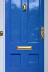 A classic blue door decorated with a door knocker, highlighting the elegance of urban decor in New England.
