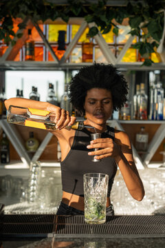 Female bartender pouring white rum from a bottle into a measurin