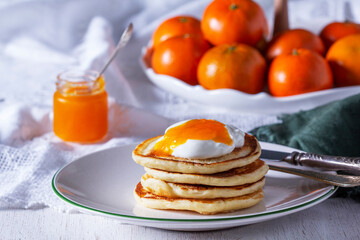 Pancakes served with tangerine jam and sour cream, and tangerines on a light background. - 753859396