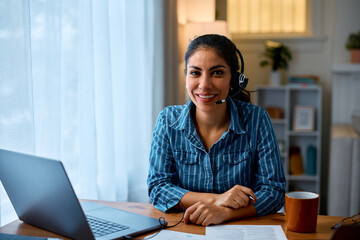 Happy Hispanic woman working remotely from home office and looking at camera.
