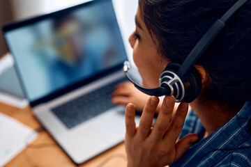 Close up of woman talking via headset while having online business meeting.