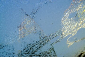 Eismuster auf Glasscheibe vor Häusern und blauem Himmel bei Sonne, Frost und Eis am Morgen im...