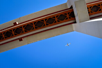 photo of the April 25 bridge in Lisbon over the Tajo River. Portugal suspension bridge on blue sky. photo taken from the bottom of the bridge. Flying plane on a blue background

