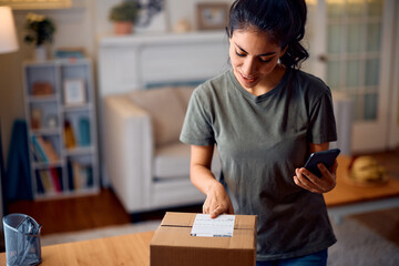 Happy woman checking label on delivered package at home. - obrazy, fototapety, plakaty