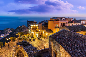 amazing evening view from mountain town to beautiful italian town with roofs and biuldings and scenic water of a sea gulf with amazing cloudy sky on background