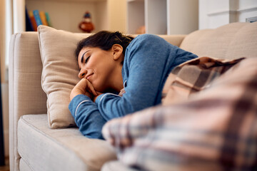 Smiling woman napping on the sofa in living room.