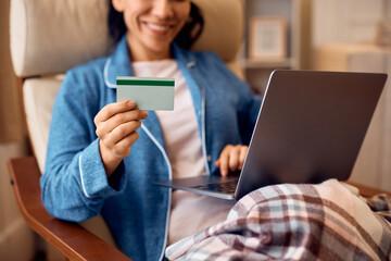 Close up of woman using credit card while checking online bank account on her laptop.