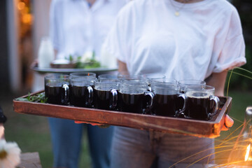 servers holding wooden tray with cups of coffee