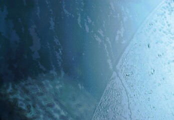 Abstraktes Motiv mit Eis- und Wassermuster vor Glasscheibe mit Licht bei Frost, Eis und Sonne am Morgen im Winter