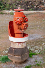 Fototapeta na wymiar A red fire hydrant with a white cap is sitting on a dirt road