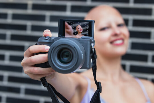 Positive young woman taking self portrait on photo camera on str