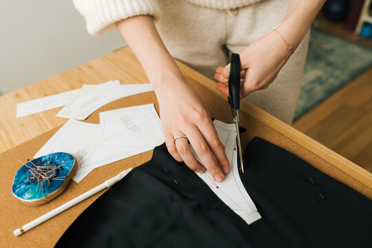 Female hands cutting fabric with pinned pattern