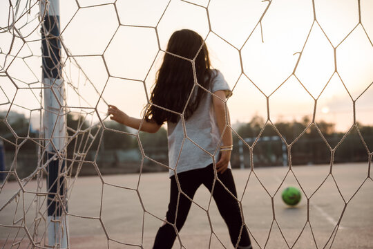Young Girl Soccer Goalkeeper Defends Football Goal at Sunset.