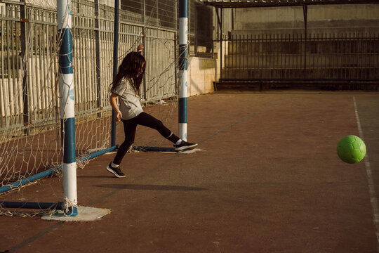 Young Girl Soccer Goalkeeper Defends Football Goal at Sunset. - Powered by Adobe