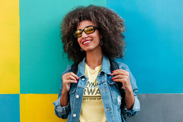 Cheerful Egyptian woman with curly hair against colorful wall