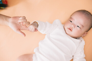 Asian Baby holds mom‘s finger.